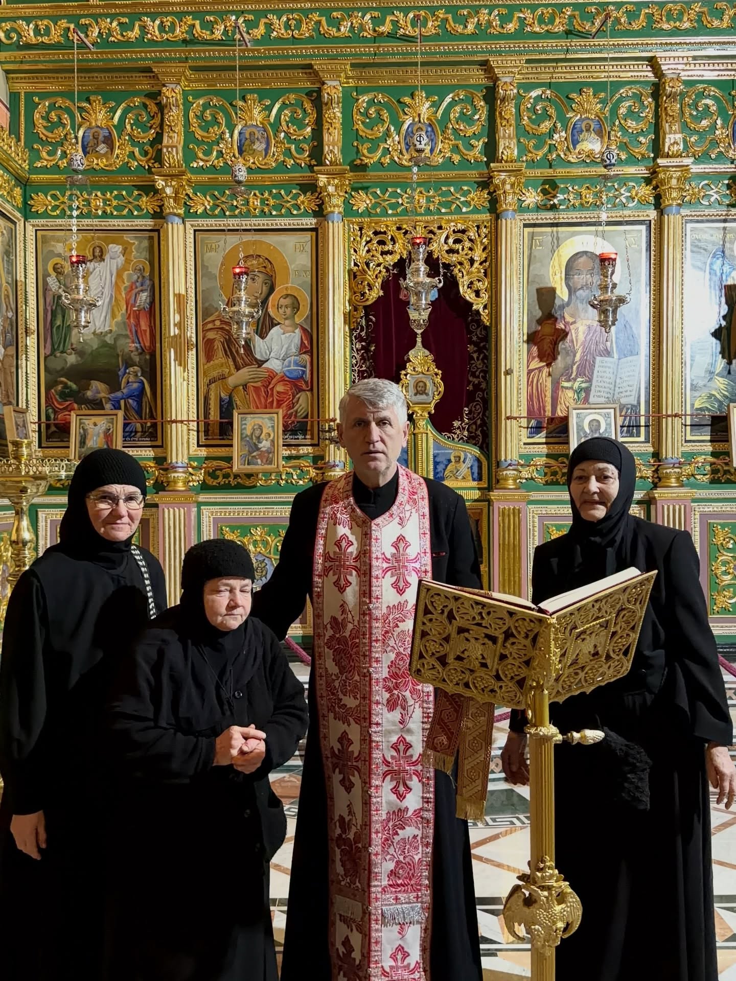 Cristian Pomohaci în biserică, îmbrăcat în straie preoțești, alături de trei măicuțe care stau în jurul lor