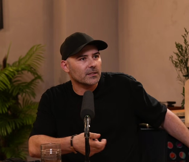 Spike &icirc;mbrăcat &icirc;n tricou negru, cu șapcă neagră pe cap, &icirc;n platoul podcastului lui Mihai Morar, st&acirc;nd la masă, cu microfonul și un pahar de apă &icirc;n față.