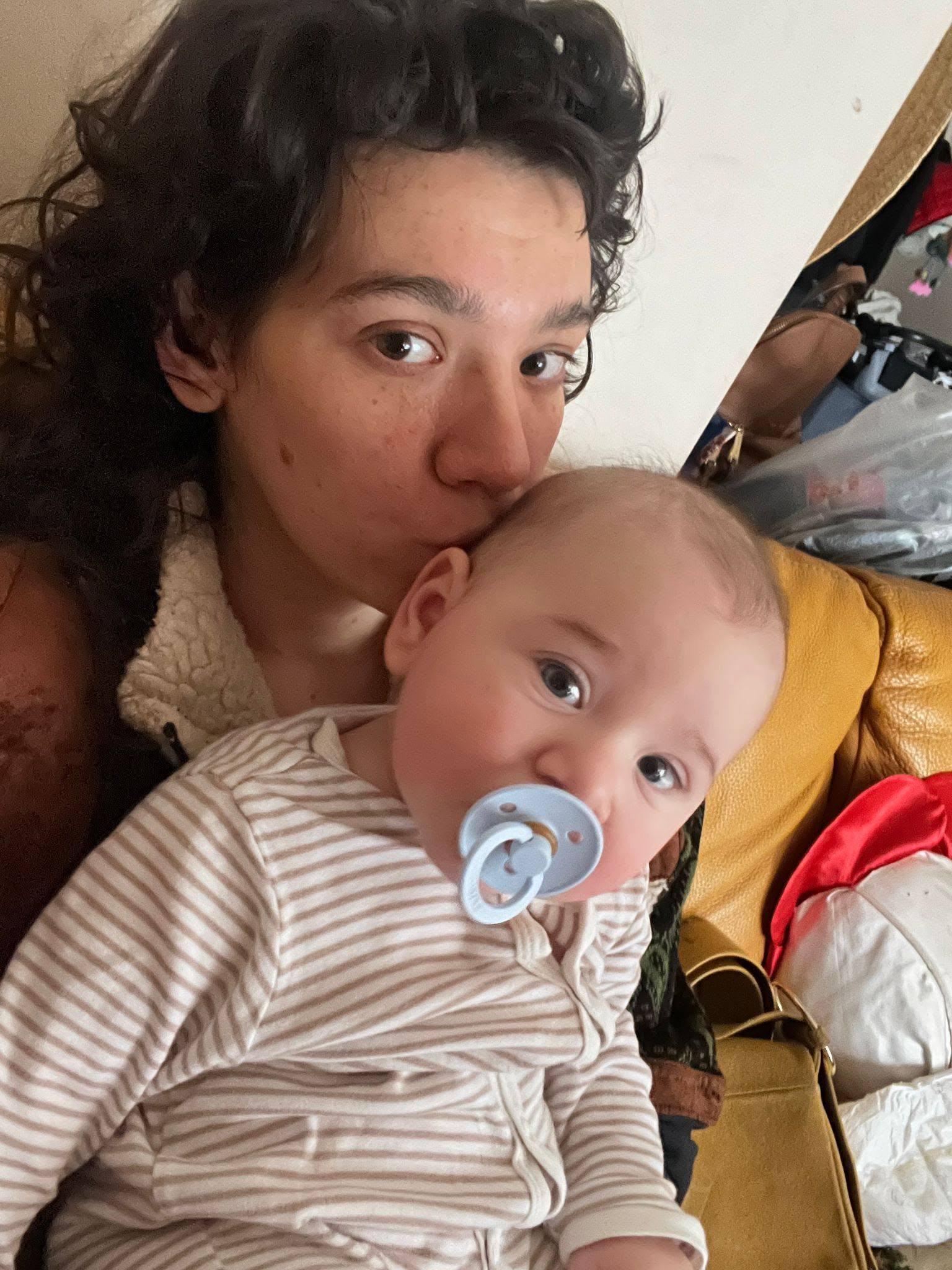 Cabiria Morgenstern țin&acirc;ndu-și fiul pe piept și sărut&acirc;ndu-l pe cap, &icirc;n timp ce acesta ține o suzetă &icirc;n gură