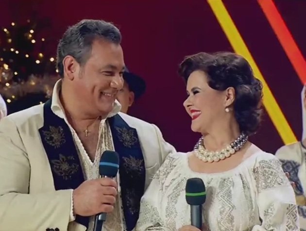 Ionuț Dolănescu și Niculina Stoican z&acirc;mbitori pe aceeași scenă, &icirc;mbrăcați &icirc;n costume populare, &icirc;n timp ce c&acirc;ntau &icirc;mpreună &icirc;n cadrul unei emisiuni TV, &icirc;nconjurați de dansatori