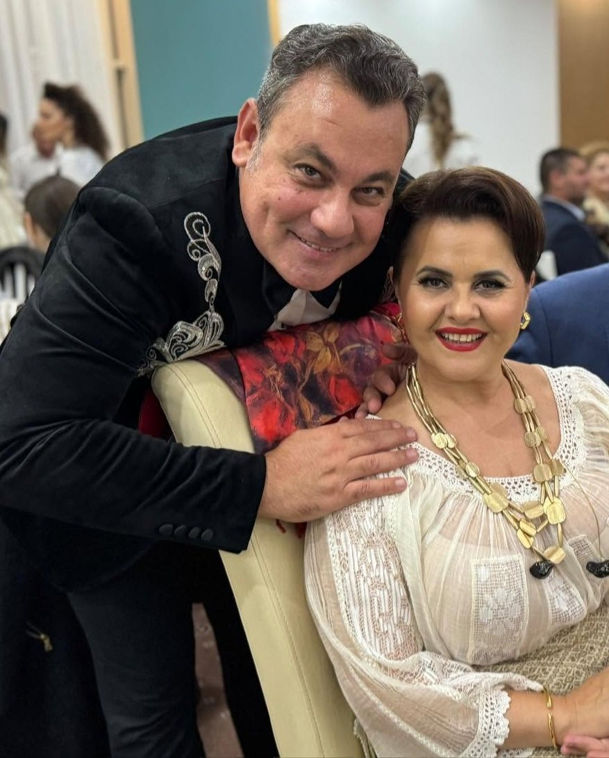 Ionuț Dolănescu alături de Niculina Stoican la o petrecere, aplecându-se peste scaunul pe care stătea ea, pentru a se fotografia împreună