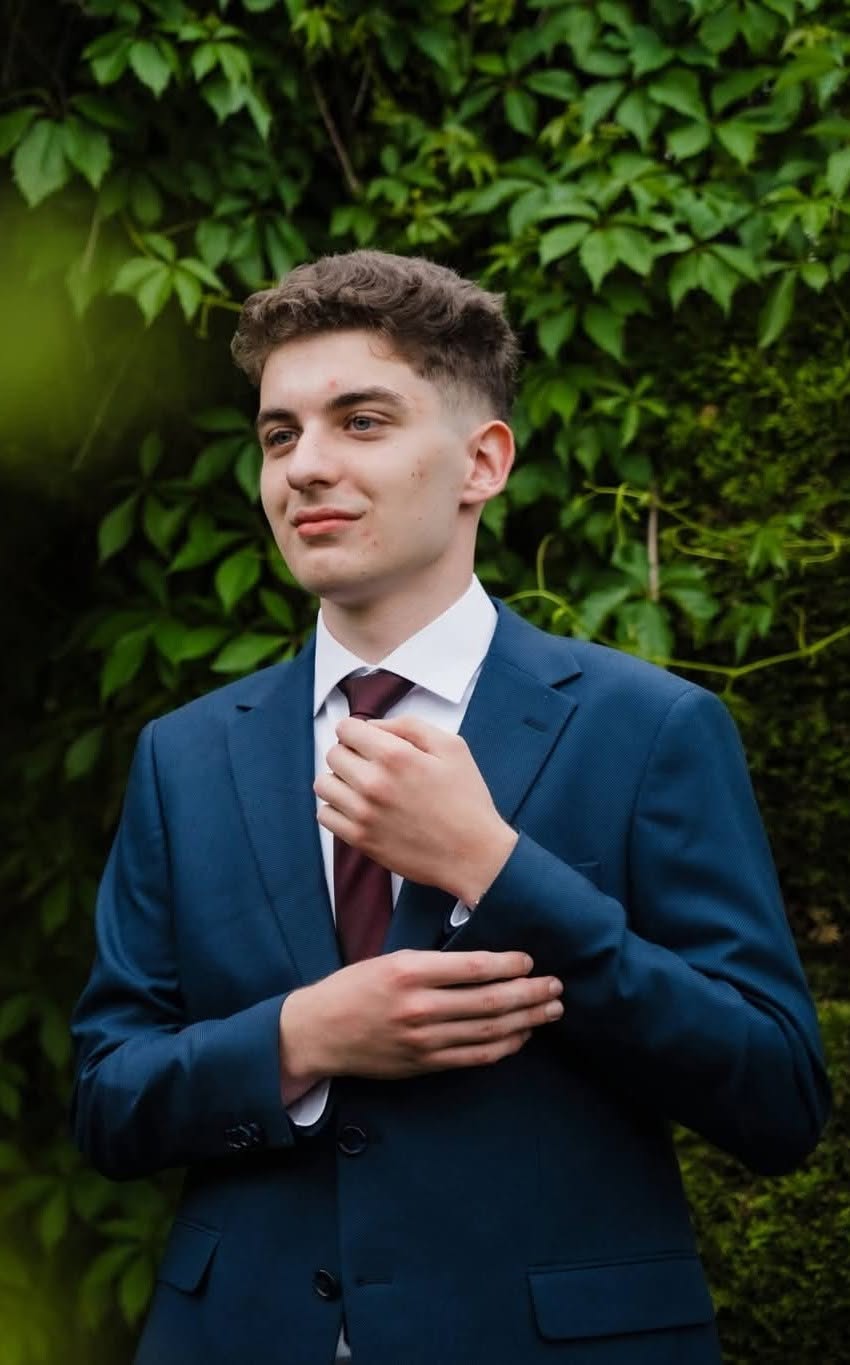 Bogdan&nbsp;Dragotă, elevul din Mediaș, &icirc;n sacou bleumarin și cămașă albă, ținută accesorizată cu o cravată maro