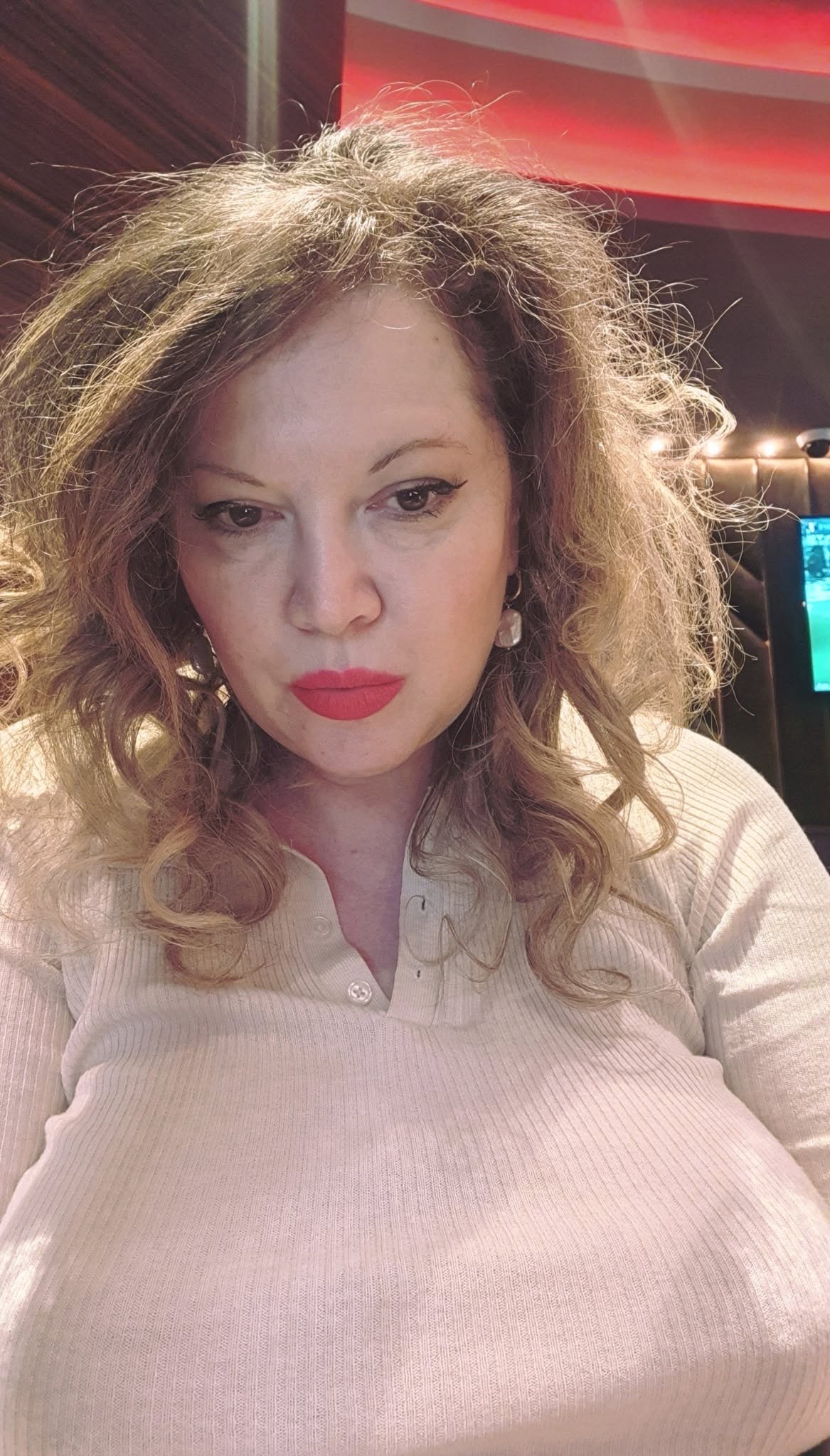 Oana Lis făc&acirc;ndu-și un selfie &icirc;n timp ce era &icirc;mbrăcată &icirc;ntr-o bluză crem, cu decolteu &icirc;n V, &icirc;n timp ce avea buzele făcute cu ruj roșu și părul așezat pe o parte, iar &icirc;n urechi purta o pereche de cercei aurii cu perle