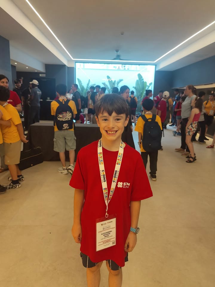 Alexander George Rusu la la Olimpiada Internațională STEM de la Roma, &icirc;ntr-un tricou roșu, purt&acirc;nd la g&acirc;t ecusonul cu numele lui