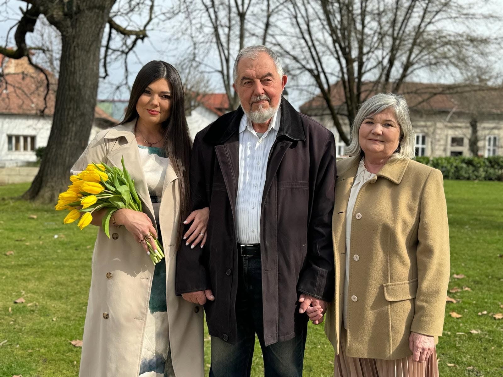 Paula Seling alături de părinții ei care se țin de m&acirc;nă, &icirc;n timp ce ea &icirc;l ține pe tatăl său de braț, iar &icirc;n cealaltă m&acirc;nă are un buchet de lalele galbene