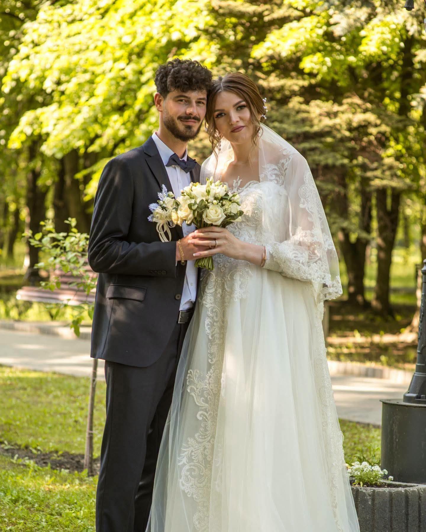Loredana și soțul ei, &icirc;n ziua nunții, &icirc;mbrăcați &icirc;n mire și mireasă, &icirc;ntr-un parc cu mulți copaci, &icirc;n timpul ședinței foto de după cununia religioasă