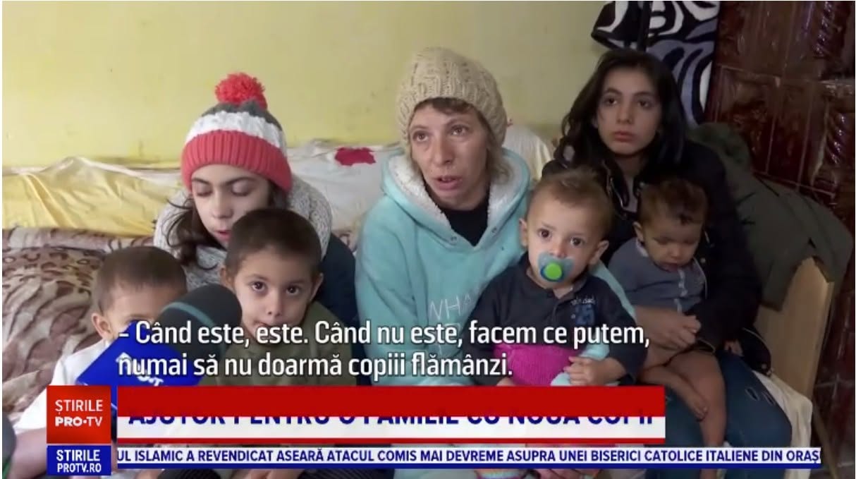 Mama Catinca alături de șase dintre cei 10 copii, st&acirc;nd &icirc;n pat l&acirc;ngă sobă, &icirc;mbrăcați &icirc;n haine de iarnă