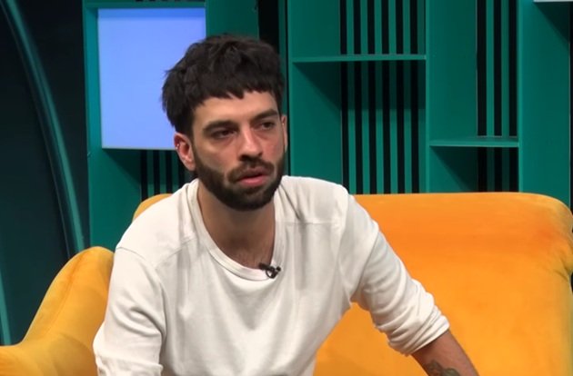 David Pușcaș &icirc;ntr-o bluză albă, cu m&acirc;necile suflecate, st&acirc;nd pe o canapea galbenă &icirc;n platoul emisiunii &bdquo;Online Story by Cornelia Ionescu&rdquo;