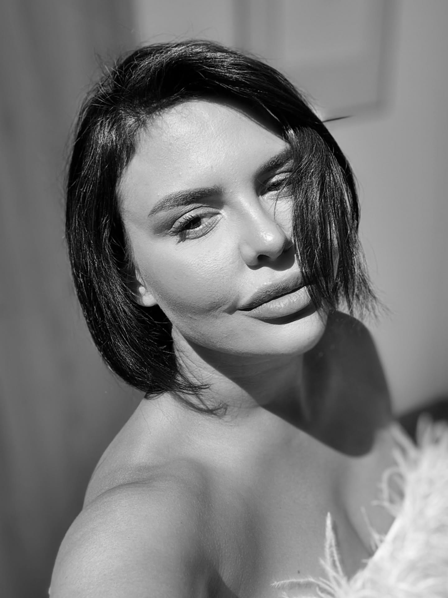 Imagine alb-negru cu Andreea Popescu &icirc;mbrăcată &icirc;ntr-o rochie albă cu pene &icirc;n zona bustului și fără bretele