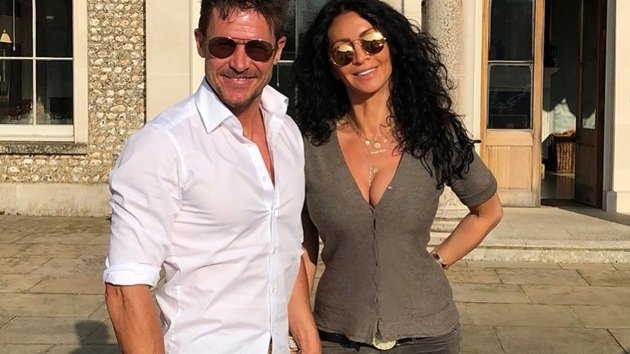 Felix Baumgartner &icirc;ntr-o cămașă albă, alături de Mihaela Rădulescu, &icirc;mbrăcată &icirc;n blugi și o bluză gri cu decolteu ad&acirc;nc, &icirc;n timp ce am&acirc;ndoi purtau ochelari de soare