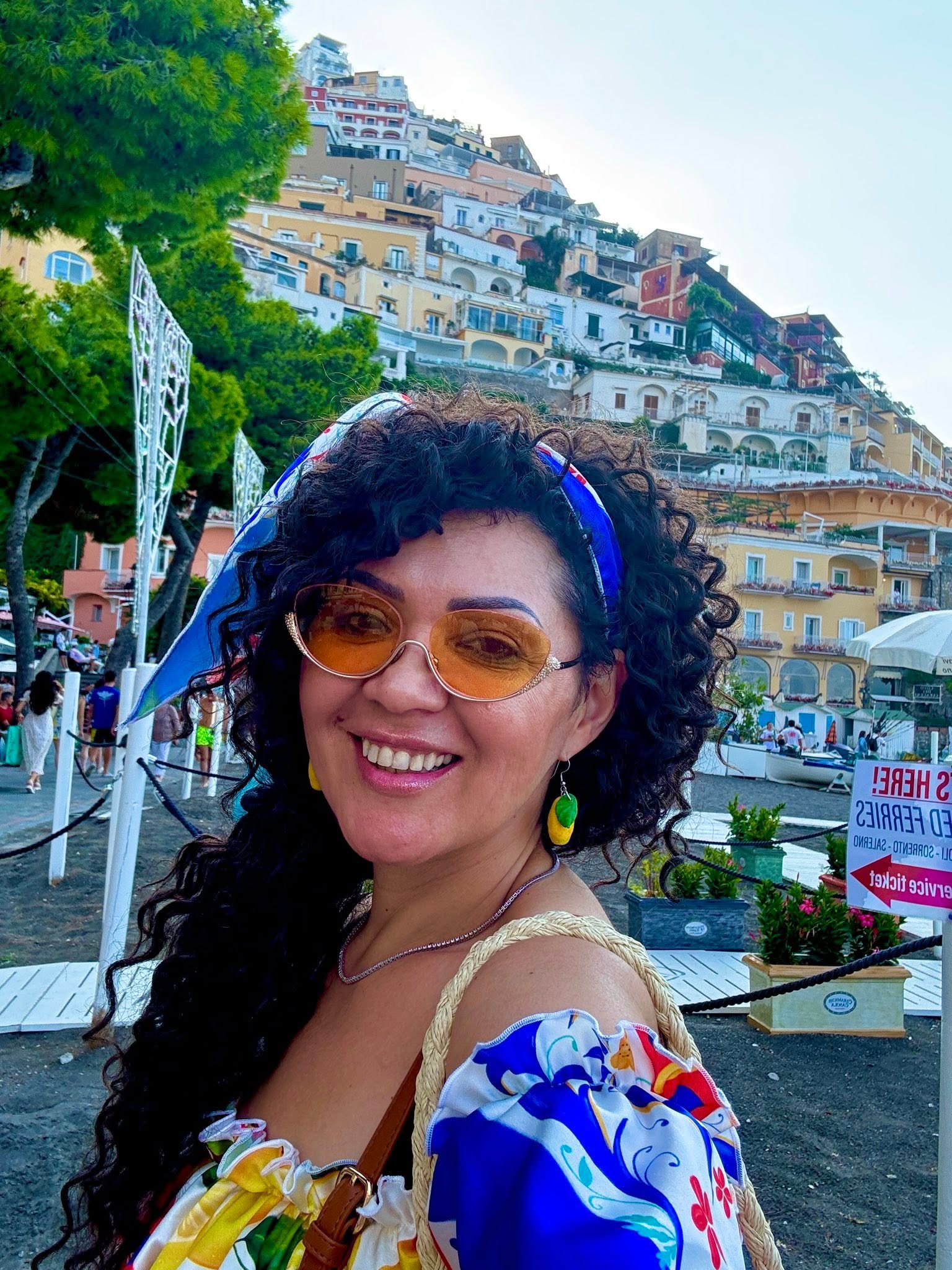 Minodora z&acirc;mbitoare, &icirc;n haine de vacanță, la mare &icirc;n Italia, făc&acirc;ndu-și un selfie cu impresionantele clădiri din Positano