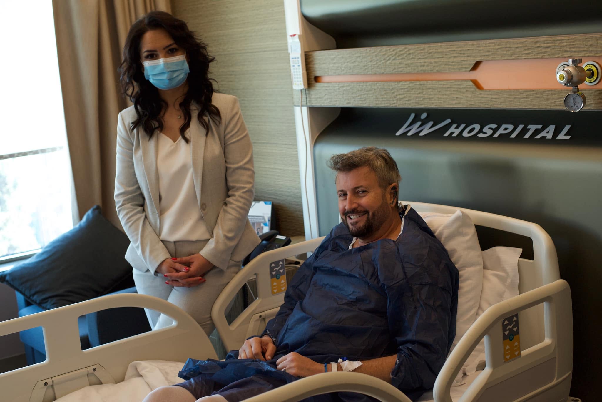 Cătălin Botezatu pe patul de spital, alături de consilierul său medical Eva Pavel, care stă l&acirc;ngă patul lui și &icirc;l &icirc;nsoțește la investigațiile pe care le are de făcut