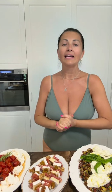 Gabriela Cristea &icirc;n costum de baie &icirc;n bucătărie, arăt&acirc;nd felurile de m&acirc;ncare pregătite pentru musafirii ei