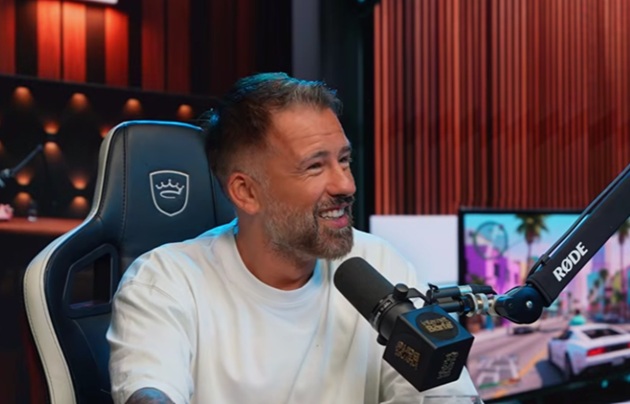 Florin Ristei z&acirc;mbitor, &icirc;ntr-un tricou alb, cu microfonul &icirc;n față, &icirc;n cadrul podcastului pe care &icirc;l are cu Speak