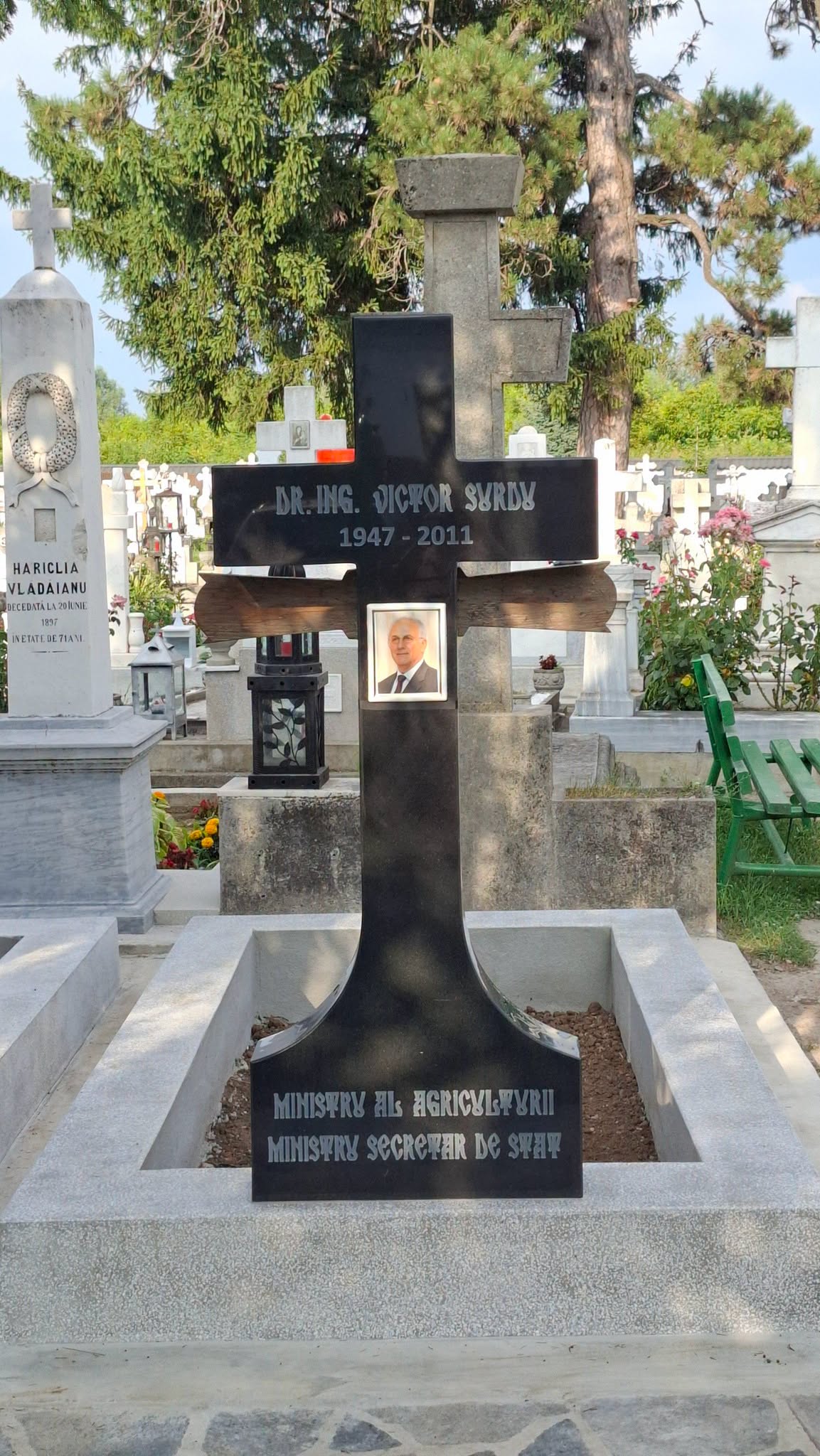 Morm&acirc;ntul lui Victor Surdu după renovare, cu bordură de ciment și cruce de marmură neagră cu poza lui