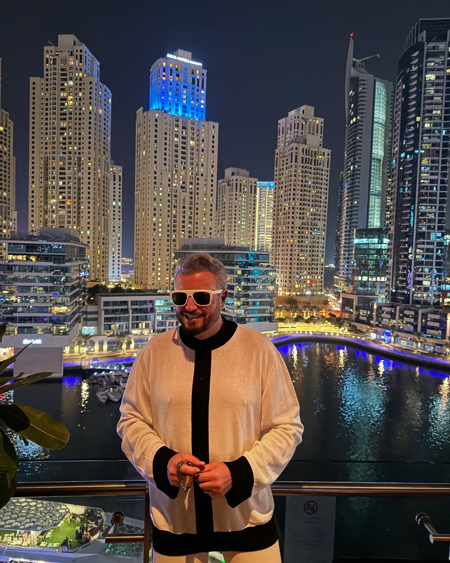 Cătălin Botezatu cu un trabuc &icirc;n m&acirc;nă și ochelari de soare la ochi, pe balconul unui apartament din Dubai