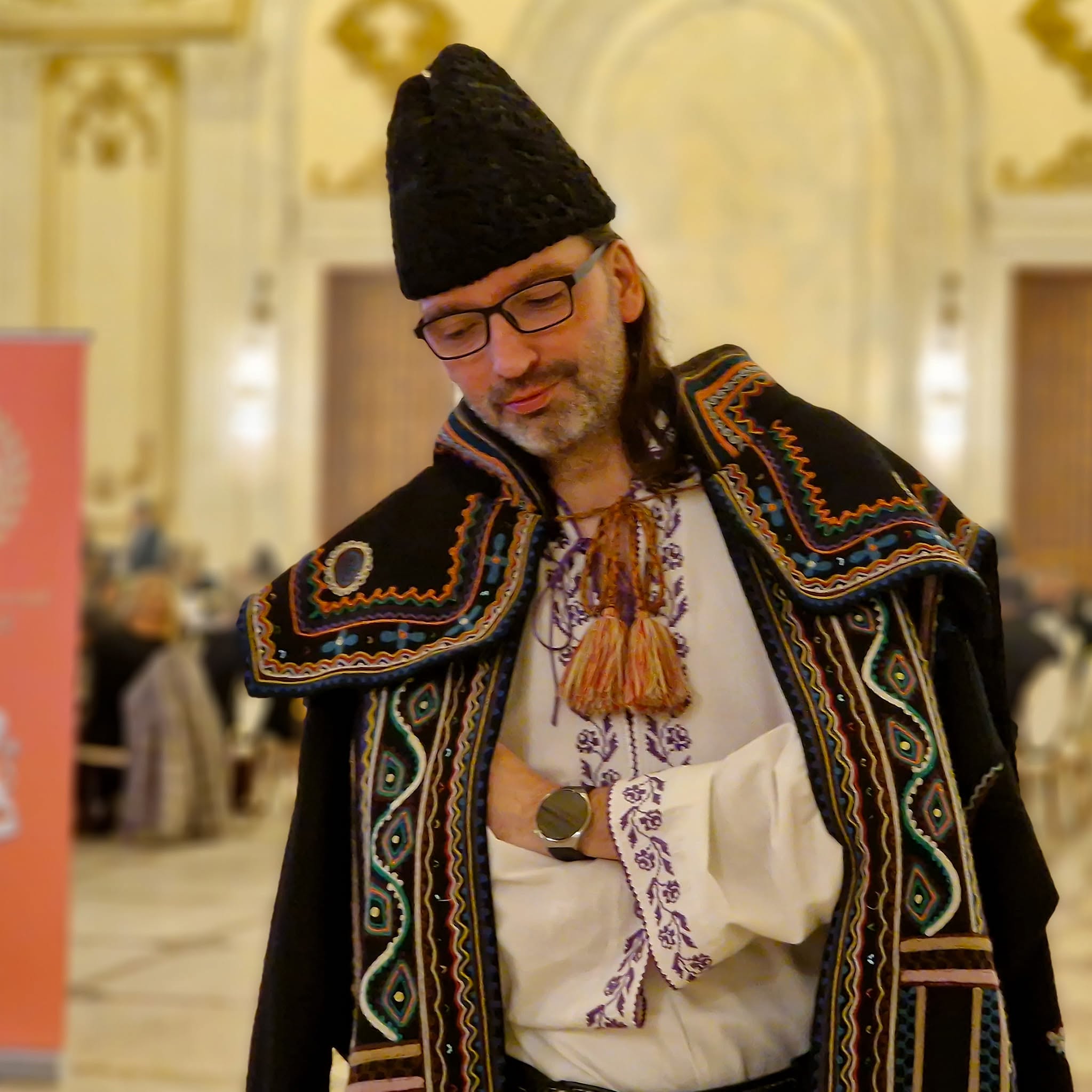 Florin Vasilică, fiul lui&nbsp;Liviu Vasilică, st&acirc;nd cu m&acirc;inile &icirc;n s&acirc;n, cu ceasul la vedere, &icirc;mbrăcat &icirc;n costum popular și cojoc cu motive tradiționale