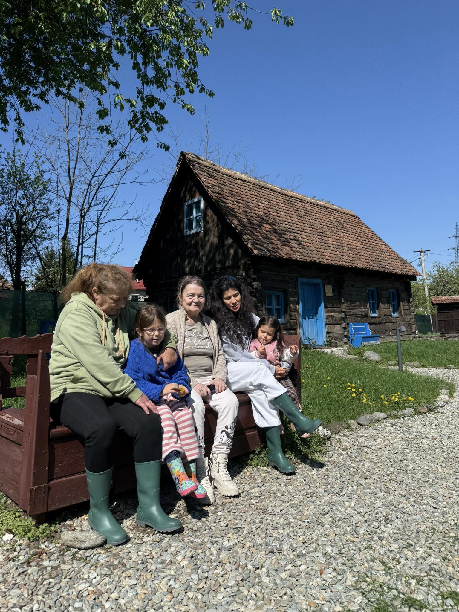Soția și fiicele lui Codin Maticiuc st&acirc;nd pe o bancă la Porumbacu de Sus, alături de bunicile fetițelor, adică mama soției și mama lui, &icirc;ncălțate cu cizme de cauciuc și bocanci
