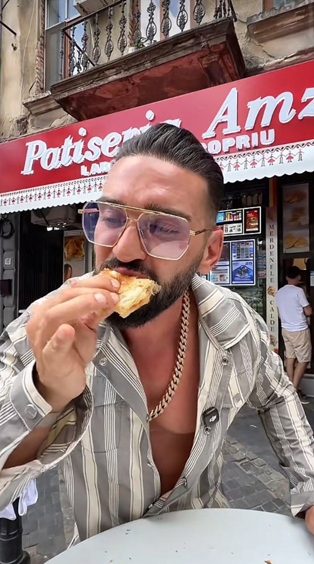 Dorian Popa degustând celebrele merdenele din Piața Amzei, în timp ce purta o cămașă cu dungi, un lanț masiv la gât și ochelari de soare