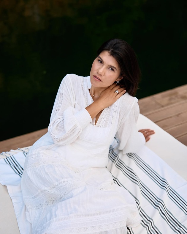 Ileana Sterp pe un ponton, așezată pe o pătură albă, &icirc;n timp ce era &icirc;mbrăcată cu o rochie lungă albă și cu părul tuns p&acirc;nă la umeri