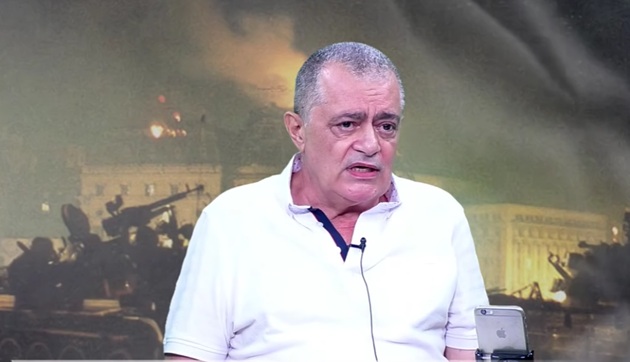 fostul deputat Cazimir Ionescu &icirc;ntr-un platou de televiziune, st&acirc;nd pe scaun, &icirc;mbrăcat &icirc;ntr-un tricou alb cu guler cu margine bleumarin