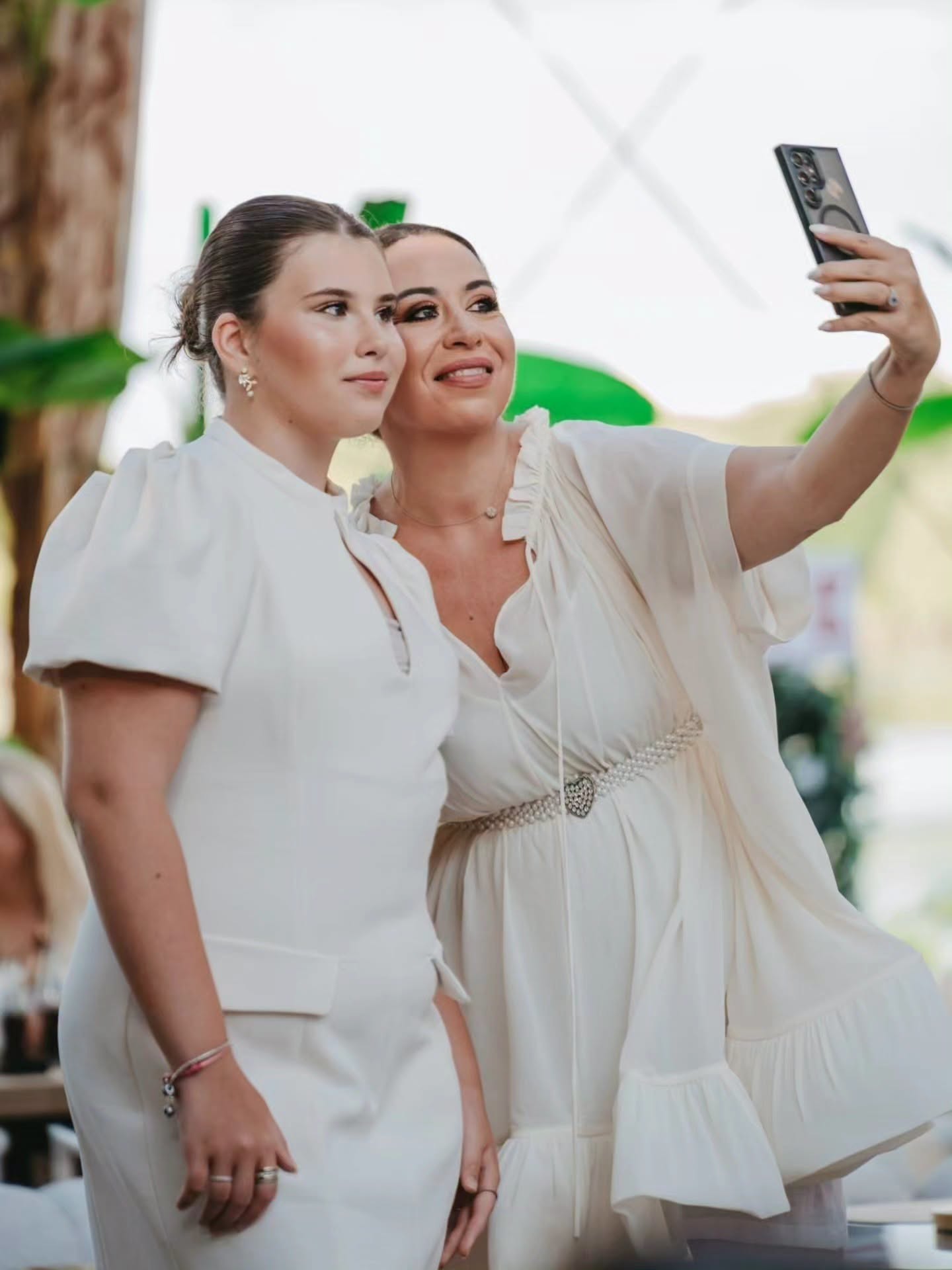 Oana Roman și fiica ei, Isabela, făc&acirc;ndu-și o fotografie cu telefonul la un eniment la care s-au &icirc;mbrăcat am&acirc;ndouă &icirc;n rochii albe și și-au prins părul &icirc;n coc