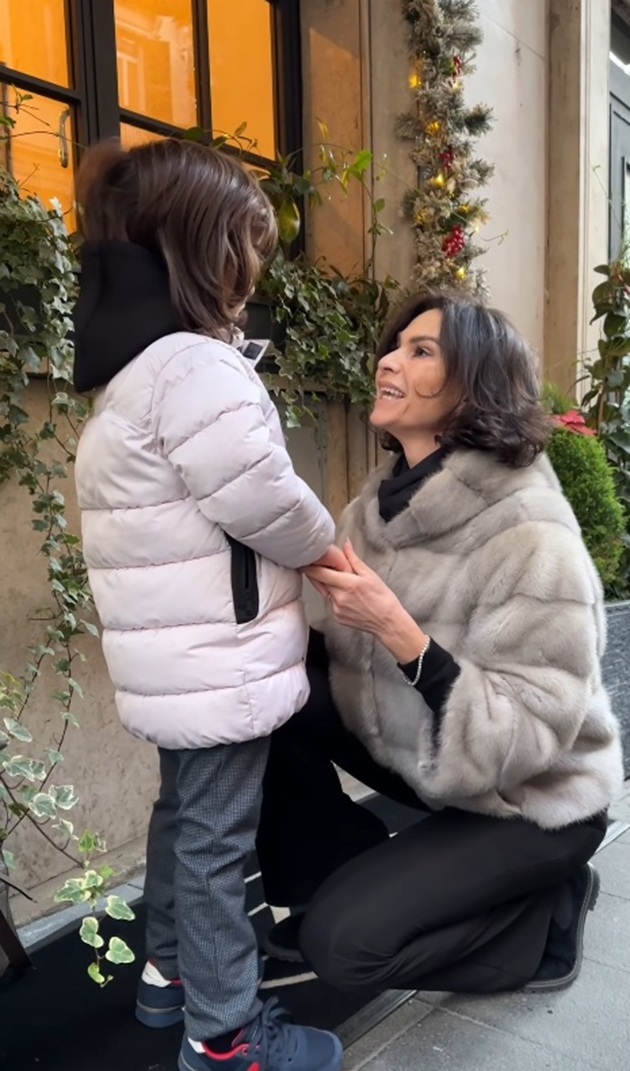 Ramona Bădescu st&acirc;nd pe vine &icirc;n fața fiului ei, Ignazio, pe un trotuar, l&acirc;ngă o clădire frumos &icirc;mpodobită, &icirc;mbrăcați &icirc;n haine groase de iarnă