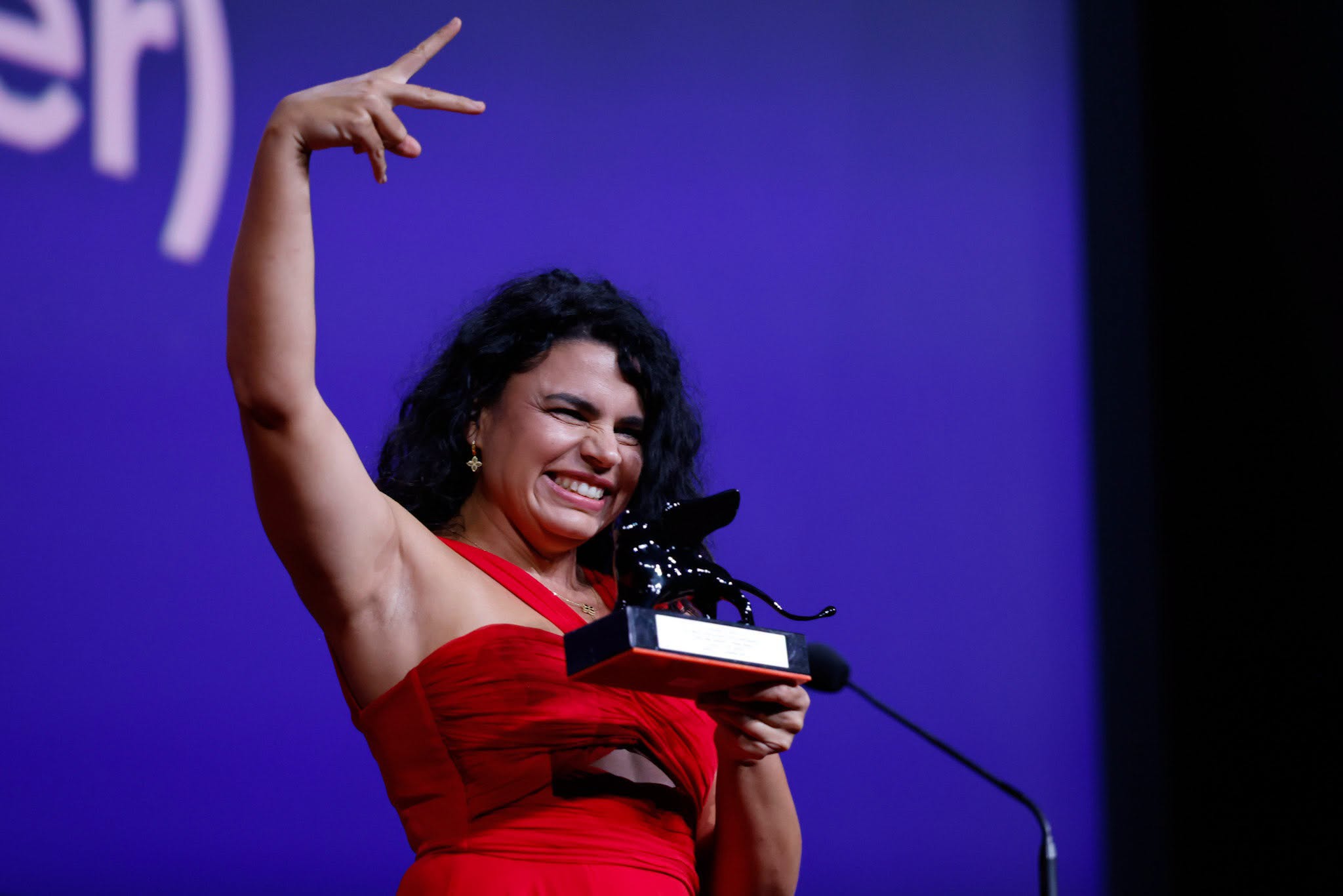 Alina Șerban &icirc;ntr-o rochie roșie, țin&acirc;nd &icirc;n m&acirc;nă premiul obținut la Veneția și bucur&acirc;ndu-se pentru reușita ei