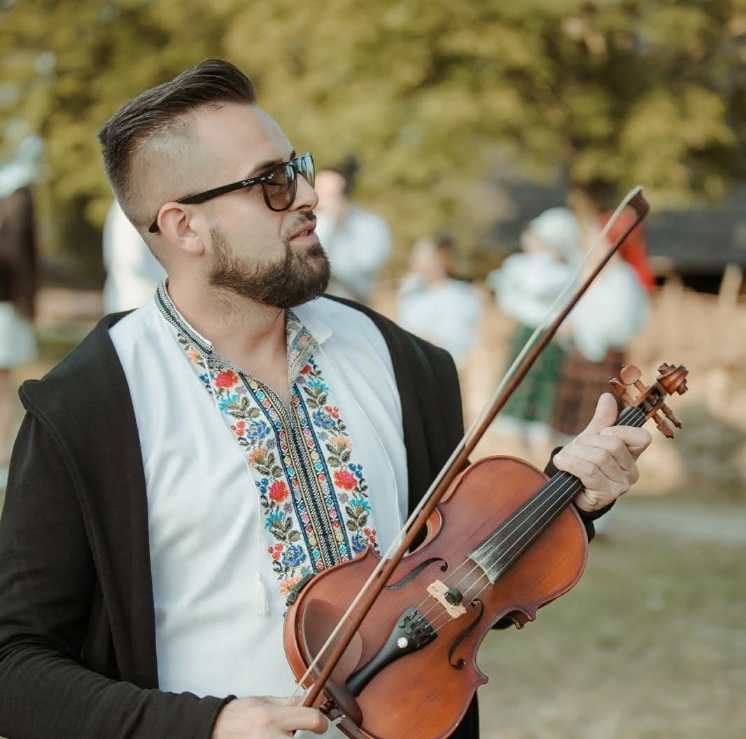 Șerban&nbsp;Horj, fostul soța al Oanei Tomoiagă, fotografiat din profil, &icirc;n costum popular, cu ochelari de soare la ochi și cu viara &icirc;n m&acirc;nă