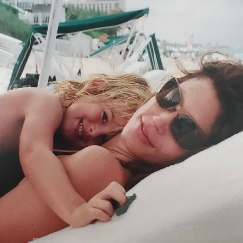 Presley Gerber la plajă, c&acirc;nd era mic, st&acirc;nd &icirc;n brațele lui Cindy Crawford care stătea &icirc;ntinsă pe șezlong și purta ochelari de soare