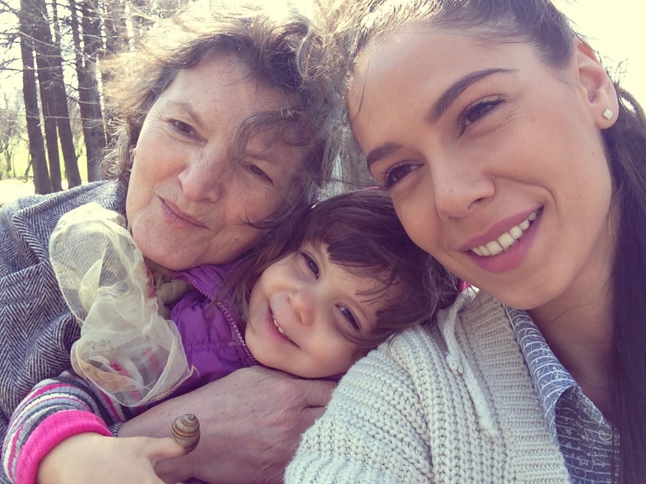 Irina Fodor z&acirc;mbitoare, la o plimbare alături de fiica ei care ține un melc pe deget și de soacra ei, mama lui Răzvan Fodor