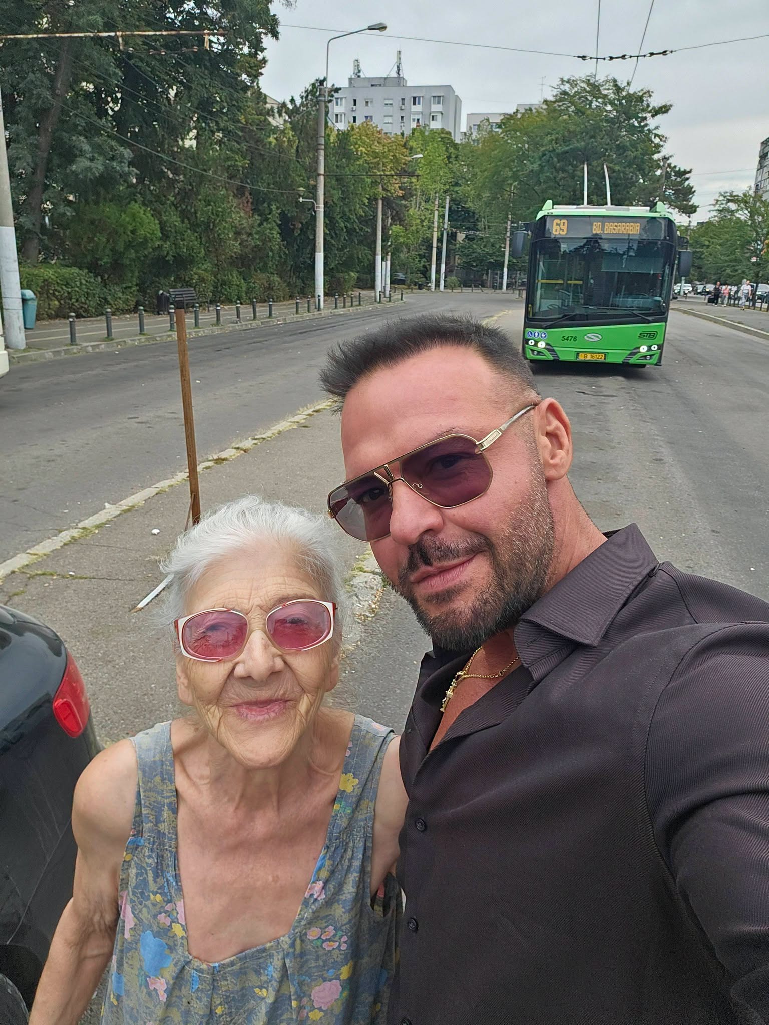 Cornel Păsat &icirc;ntr-o stație de troleu alături de mama sa, &icirc;n timp ce purtau am&acirc;ndoi ochelari la ochi