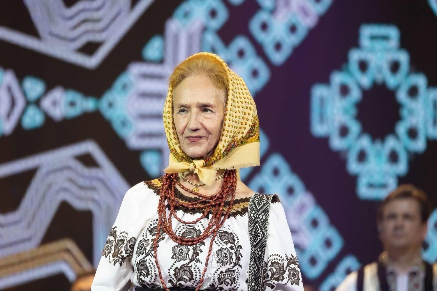 Sofia Vicoveanca pe scenă, &icirc;n costum popular, cu batic pe cap, privind spre publicul ei