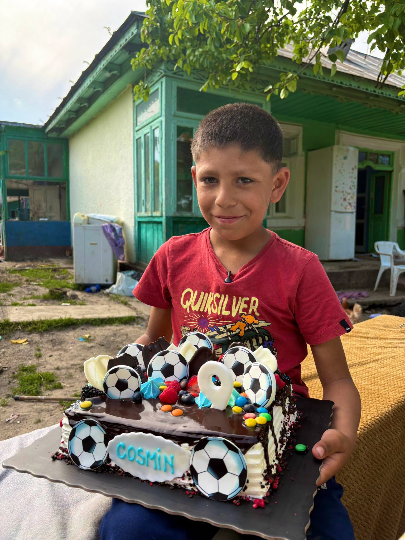 Cosmin ținându-și tortul primit la ziua sa de naștere, tort decorat cu mingi de fotbal care arată marea sa pasiune