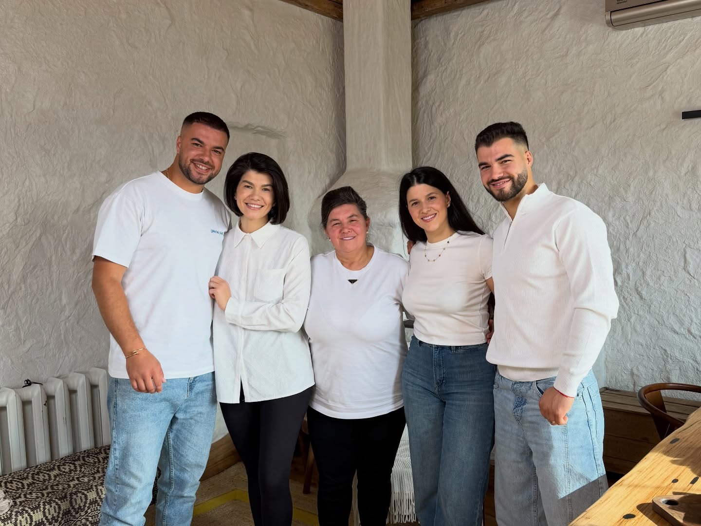Frații Sterp alături de mama Geta, &icirc;mbrăcați toți &icirc;n tricouri albe, z&acirc;mbitori &icirc;ntr-o &icirc;ncăpere rustică