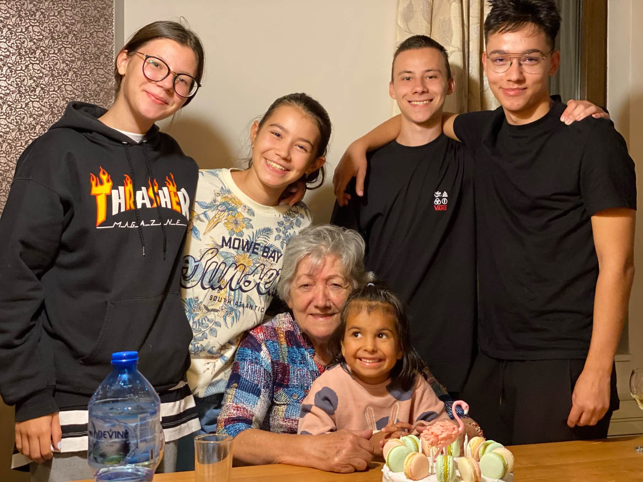 Cornelia Naum, mama lui Victor Ponta, st&acirc;nd la masă, cu un tort &icirc;n față și cu nepoții &icirc;n jurul ei