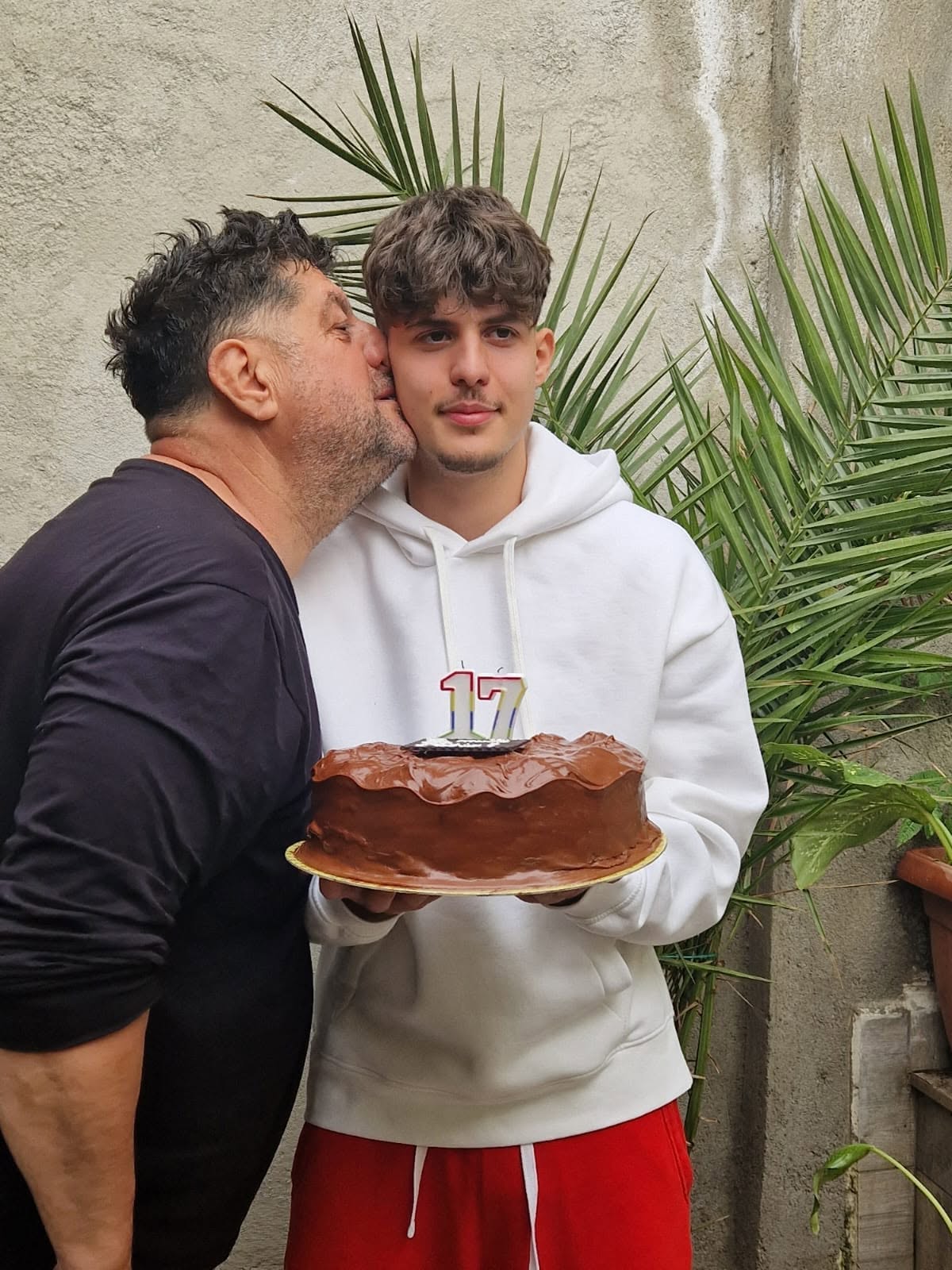 Tavi Colen sărut&acirc;ndu-l pe fiul lui pe obraz, la aniversarea acestuia de 17 ani, &icirc;n timp ce adolescentul ținea un tort &icirc;n m&acirc;nă