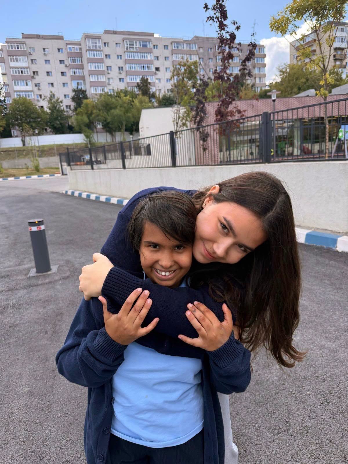 Maria z&acirc;mbitoare, alături de sora ei mai mare, Irina Ponta, care o &icirc;mbrățișează str&acirc;ns și &icirc;și apleacă capul peste umărul ei