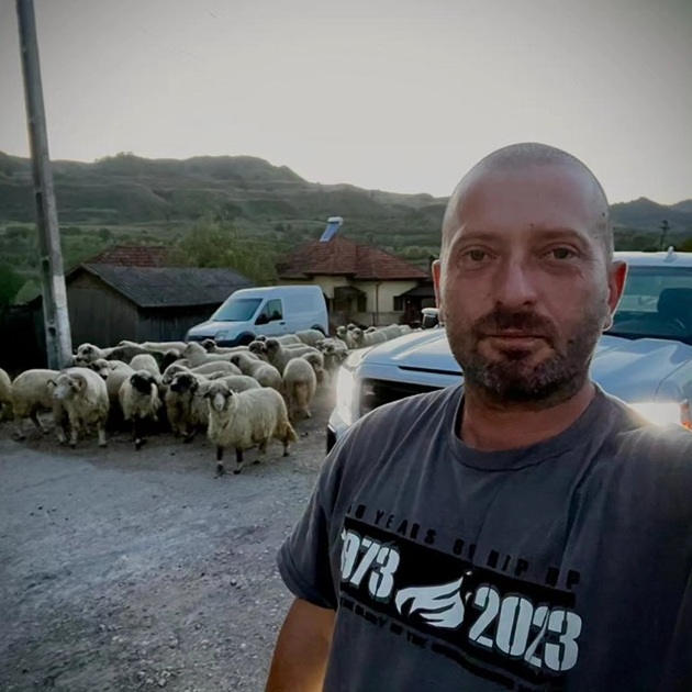 Cheloo undeva la munte, făc&acirc;ndu-și un selfie &icirc;n timp ce &icirc;n spatele lui erau mai multe mașini și o turmă de oi