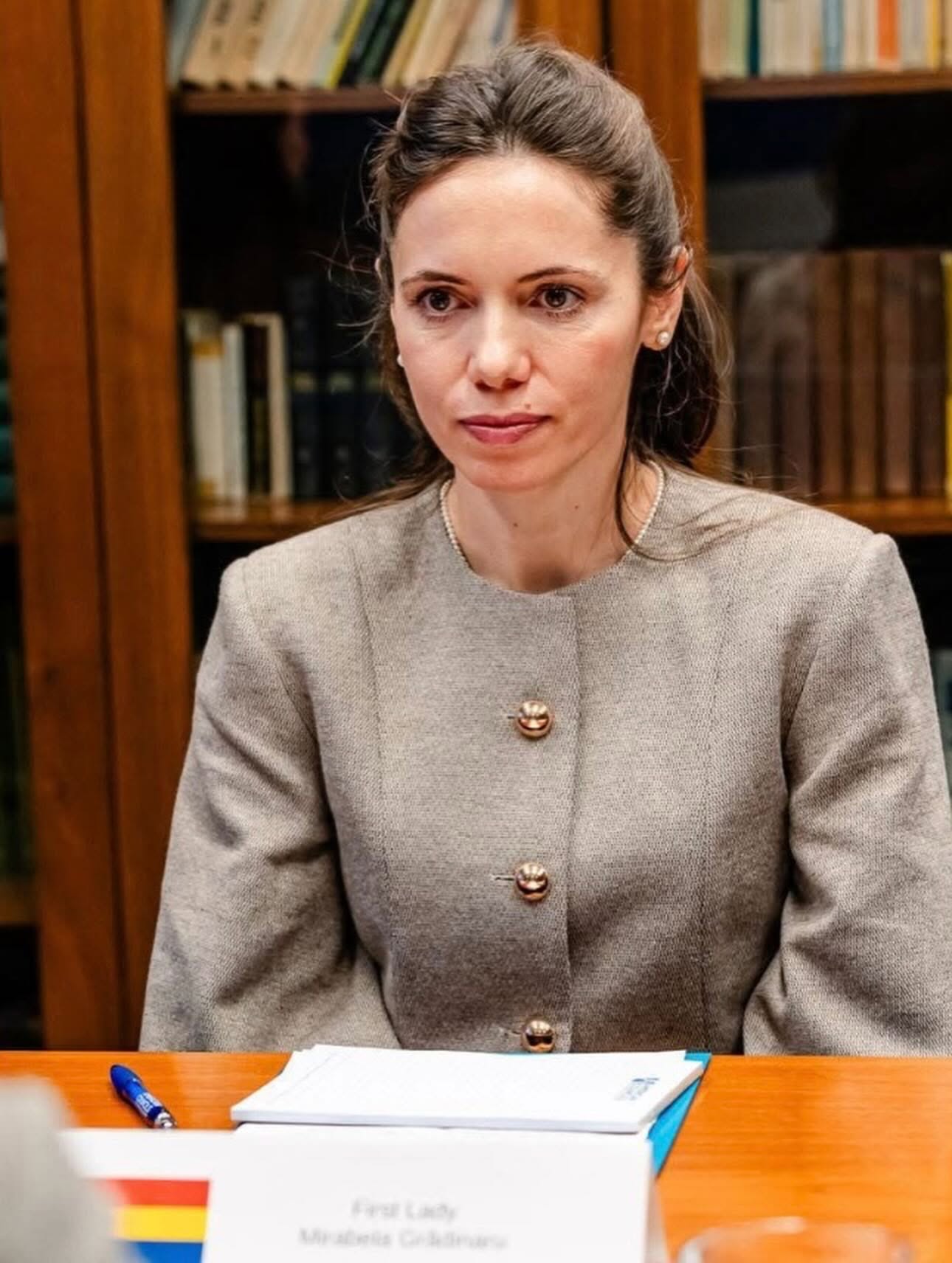 Mirabela Grădinaru, partenera lui Nicușor Dan, &icirc;ntr-un sacou gri, st&acirc;nd la un birou, &icirc;n timp ce purta perle la g&acirc;t și &icirc;n urechi și părul prins la spate