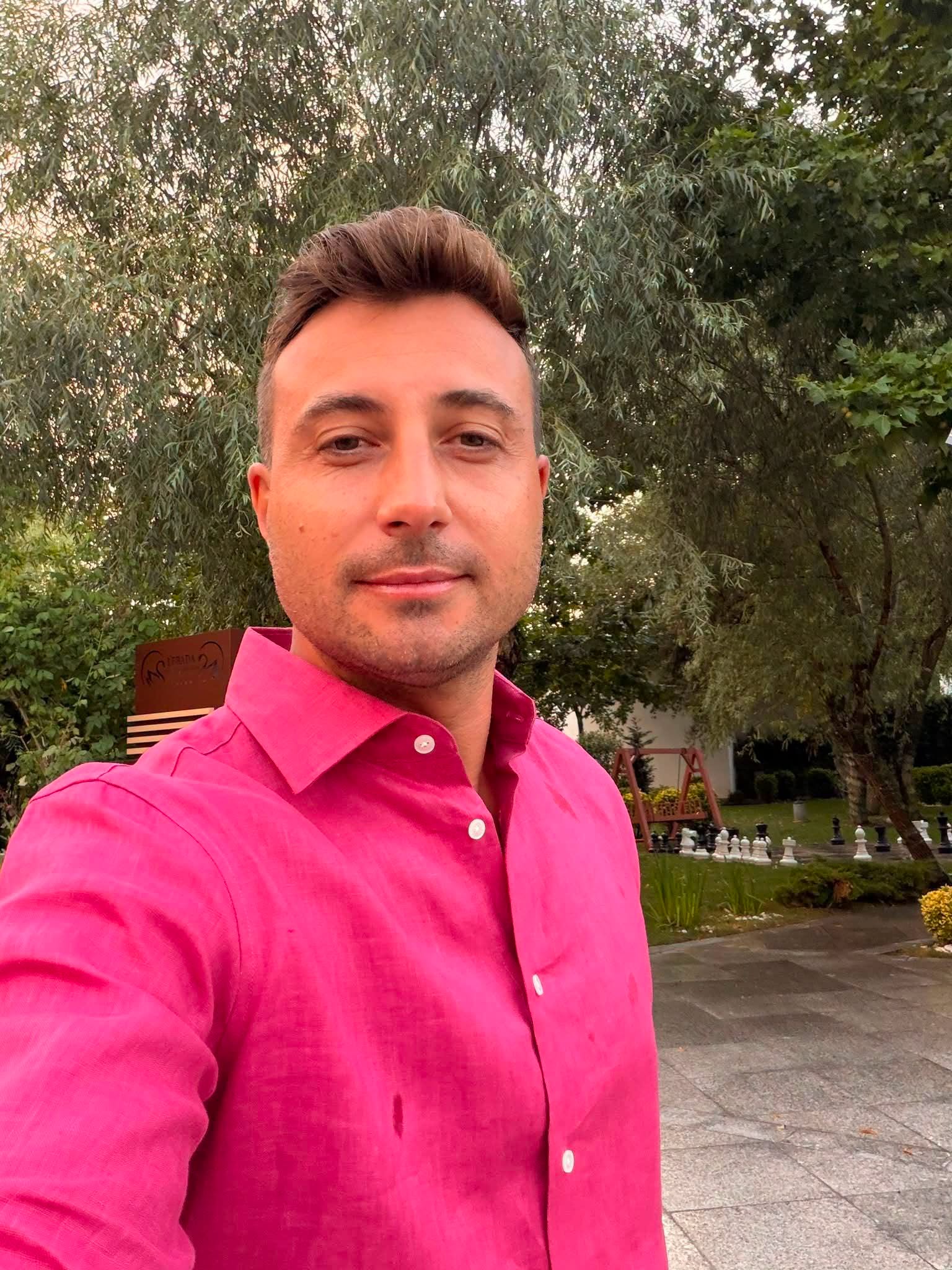 Valentin Sanfira &icirc;ntr-o cămașă roz, făc&acirc;ndu-și un selfie