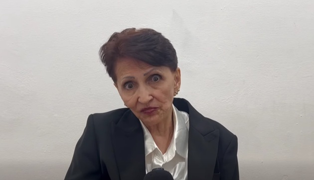 Dida Drăgan &icirc;n sacou negru și cămașă albă, cu părul tuns scurt și cu microfonul &icirc;n față, &icirc;n timpul unui interviu