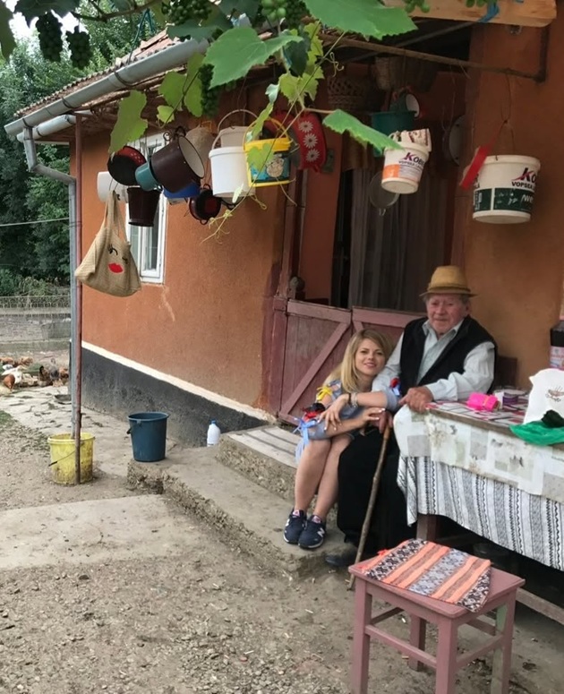 Roxana Hulpe stând pe pragul casei alături de bunicul ei care stătea pe un scaun și se sprijinea în baston