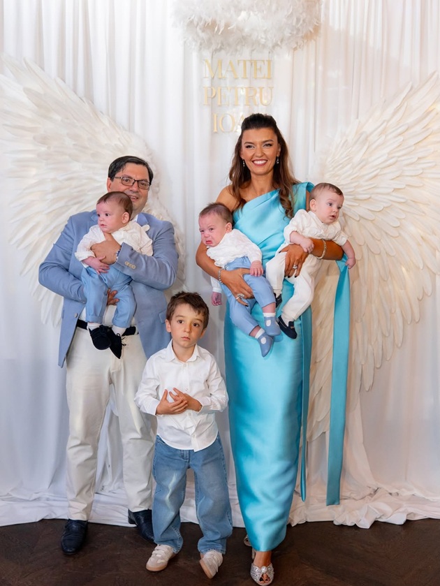 Mihaela și Nicolae Bănicioiu alături de cei patru copii ai lor, la panoul foto de la botezul tripleților, îmbrăcați toți asortat în alb și bleu