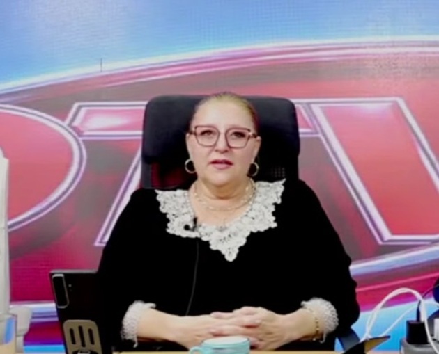 Diana Șoșoacă după ce a slăbit 20 de kg, st&acirc;nd pe scaun &icirc;n emisiunea lui Dan Diaconescu, &icirc;mbrăcată &icirc;ntr-o bluză neagră cu guler alb din dantelă