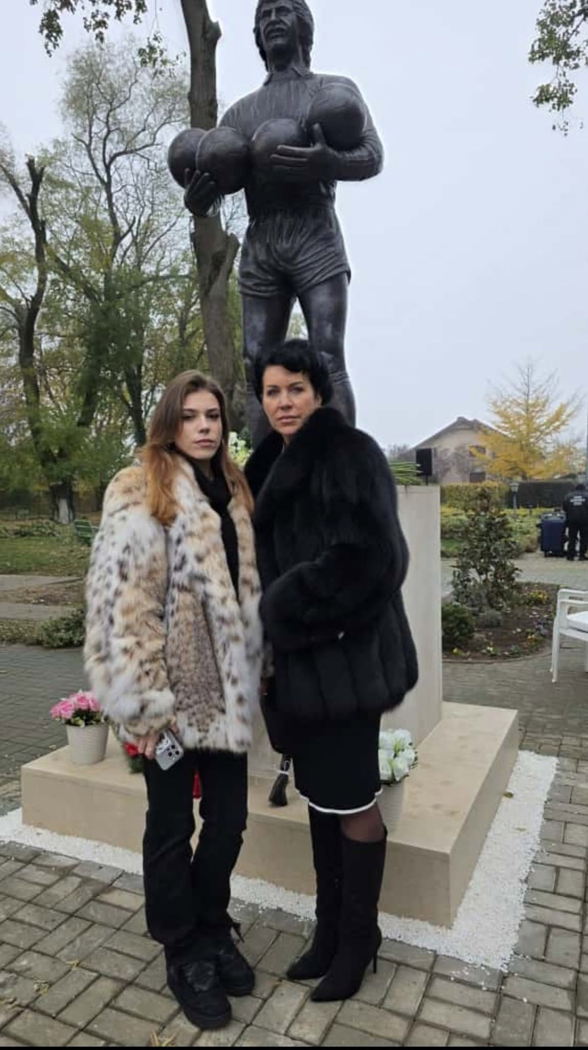 Alexandra Duckadam, văduva fostului fotbalist, alături de fiica lor, Julianne, &icirc;mbrăcate cu haine de blană, st&acirc;nd am&acirc;ndouă l&acirc;ngă statuia lui Helmut Duckadam