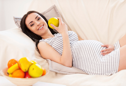 femeie gravida mancand fructe